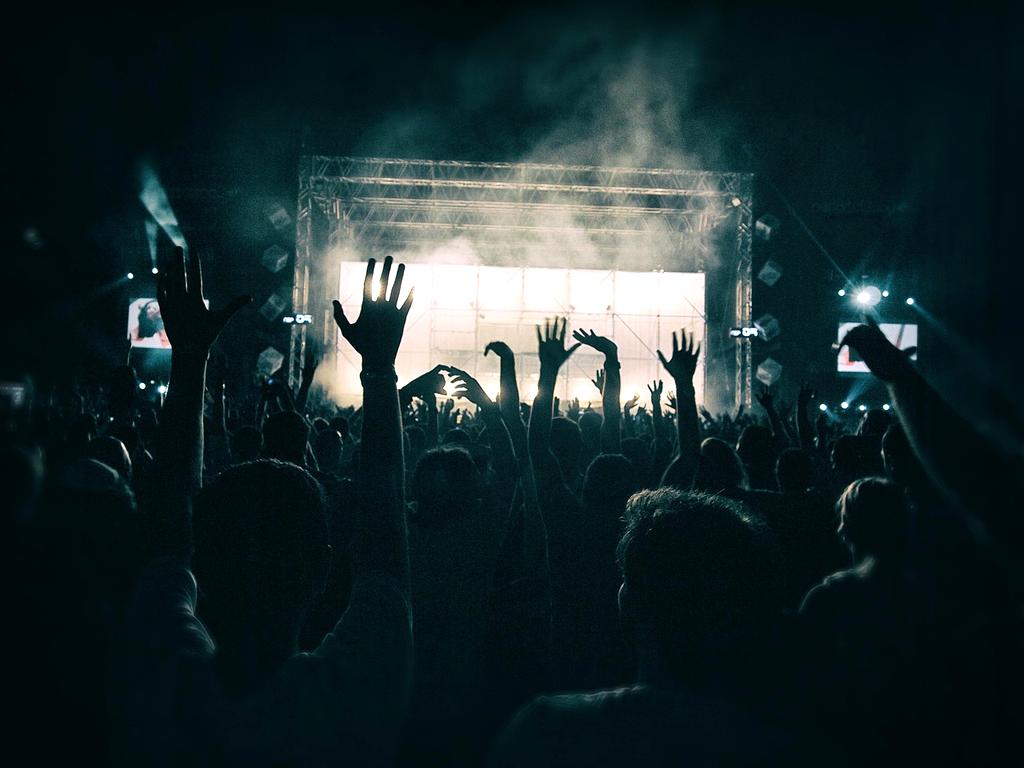 Feiernde Menge vor einer Bühne mit bunten Lichtern